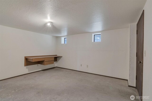 basement with baseboards and a textured ceiling
