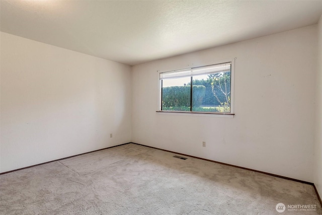 carpeted empty room featuring baseboards