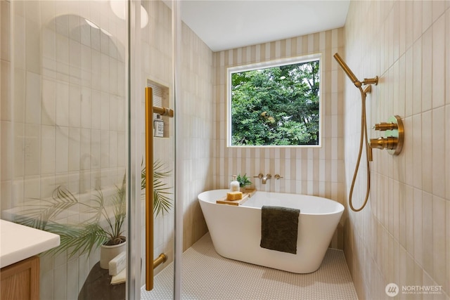 bathroom featuring a soaking tub, tile walls, and tiled shower