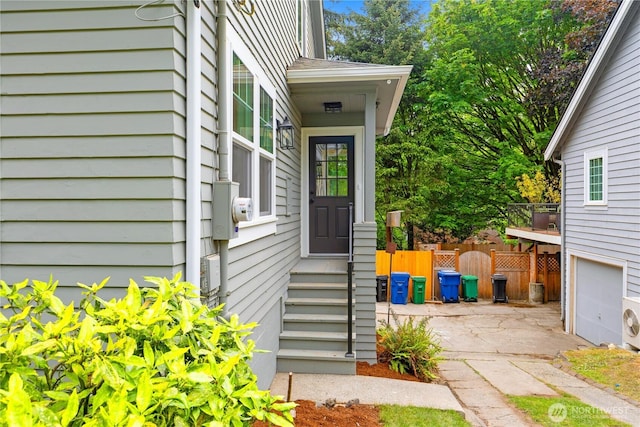 doorway to property with a garage and fence