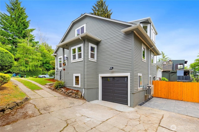 view of property exterior featuring fence, an attached garage, and concrete driveway