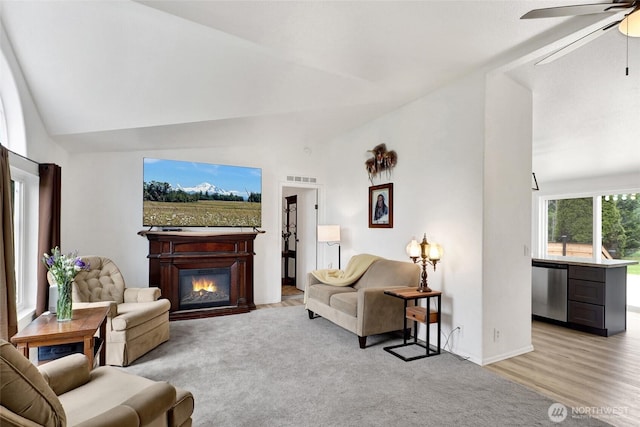 7135 W 40th Dr, Ferndale, WA 98248 - living area with vaulted ceiling, a ceiling fan, a glass covered fireplace, baseboards, and light colored carpet