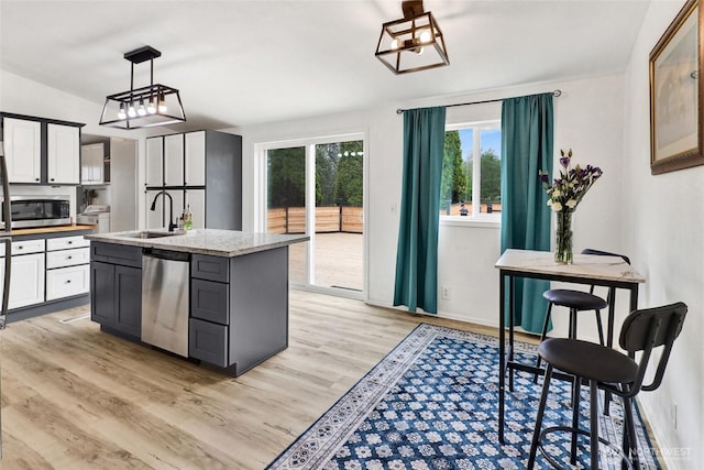 7135 W 40th Dr, Ferndale, WA 98248 - kitchen featuring stainless steel appliances, a sink, light wood-style flooring, and an island with sink