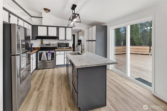 7135 W 40th Dr, Ferndale, WA 98248 - kitchen with stainless steel appliances, a sink, under cabinet range hood, white cabinetry, and vaulted ceiling