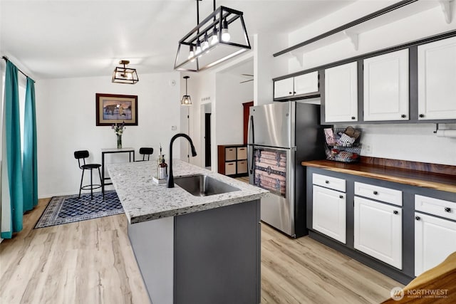7135 W 40th Dr, Ferndale, WA 98248 - kitchen with a sink, freestanding refrigerator, light wood-style floors, white cabinets, and dark stone countertops