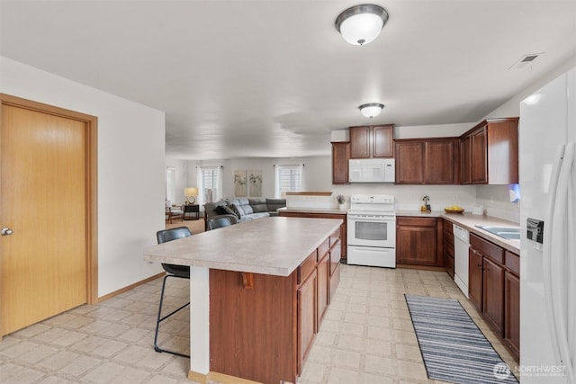 9604 201st Street Ct E, Graham, WA 98338 - kitchen featuring white appliances, light flooring, light countertops, and a breakfast bar area