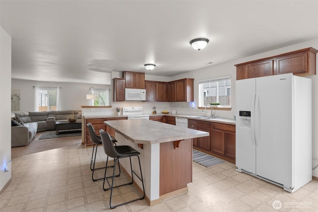 9604 201st Street Ct E, Graham, WA 98338 - kitchen featuring white appliances, light flooring, open floor plan, and a breakfast bar area