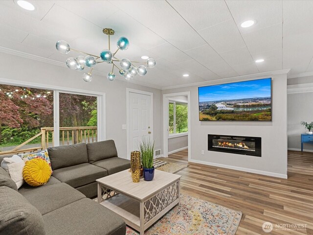 28611 139th Ave NE, Arlington, WA 98223 - living room featuring crown molding, baseboards, wood finished floors, a chandelier, and a glass covered fireplace