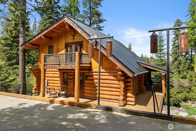 view of front of house featuring log exterior, metal roof, a wooden deck, and stairway