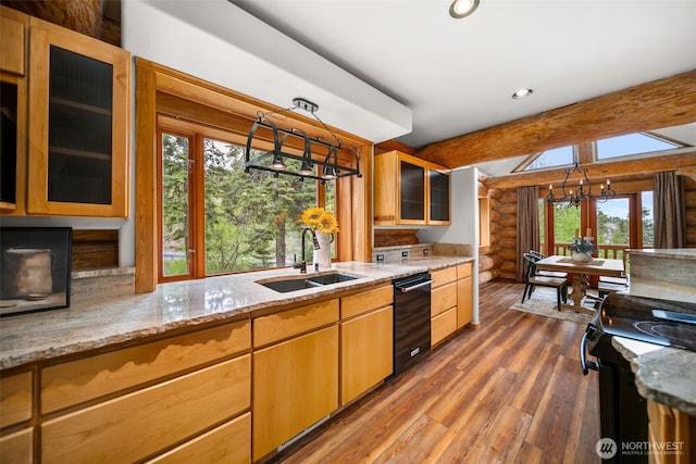 kitchen with a sink, black appliances, healthy amount of natural light, log walls, and wood finished floors
