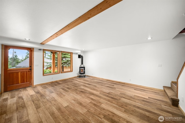 unfurnished living room with a wood stove, light wood-style flooring, stairway, beamed ceiling, and recessed lighting