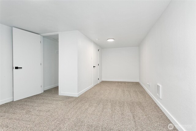 empty room featuring light colored carpet and baseboards
