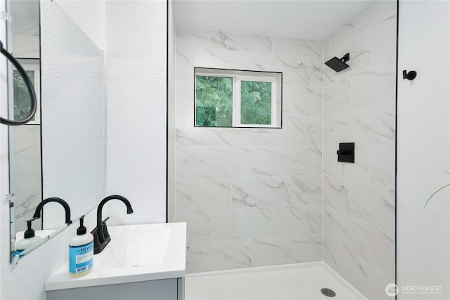 bathroom featuring tiled shower and vanity