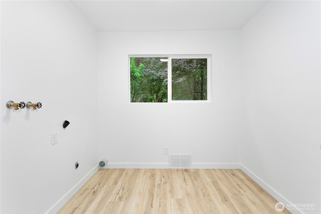 laundry area with light wood finished floors, hookup for an electric dryer, and baseboards