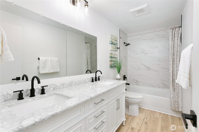 full bath featuring toilet, wood finished floors, double vanity, and shower / tub combo