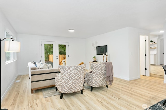living room with french doors, light wood-style floors, and baseboards