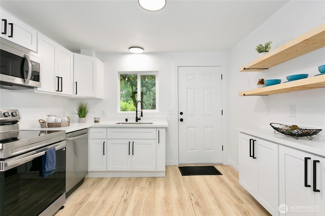 kitchen with stainless steel appliances, a sink, light wood-style floors, light countertops, and white cabinets