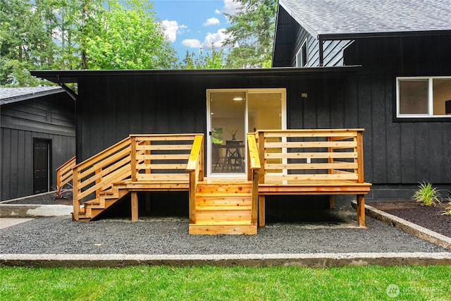 rear view of property featuring a wooden deck, roof with shingles, and stairs