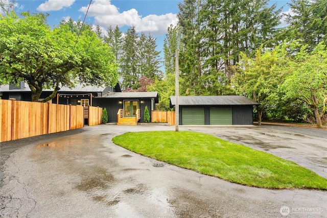 mid-century inspired home with fence, a detached garage, and an outdoor structure