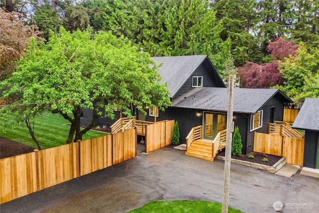 view of front facade with a shingled roof, french doors, fence, and a deck