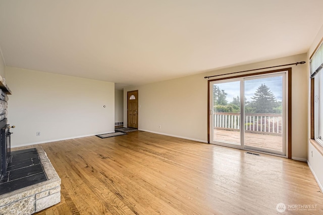 1204 S 229th St, Des Moines, WA 98198 - unfurnished living room featuring light wood-style flooring, a stone fireplace, and baseboards