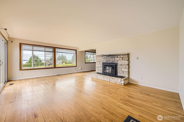 1204 S 229th St, Des Moines, WA 98198 - unfurnished living room featuring light wood finished floors, baseboards, and a stone fireplace