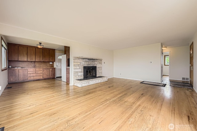 1204 S 229th St, Des Moines, WA 98198 - unfurnished living room featuring light wood-type flooring, a stone fireplace, and baseboards