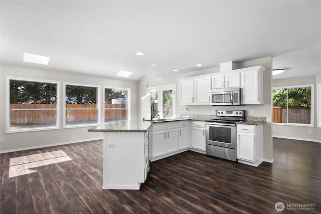 10901 194th Street Ct E, Graham, WA 98338 - kitchen with stainless steel appliances, a peninsula, dark wood-style flooring, a skylight, and white cabinets
