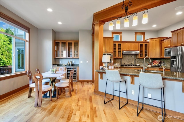 6611 Waterton Cir, Mukilteo, WA 98275 - kitchen with appliances with stainless steel finishes, under cabinet range hood, beverage cooler, brown cabinets, and recessed lighting