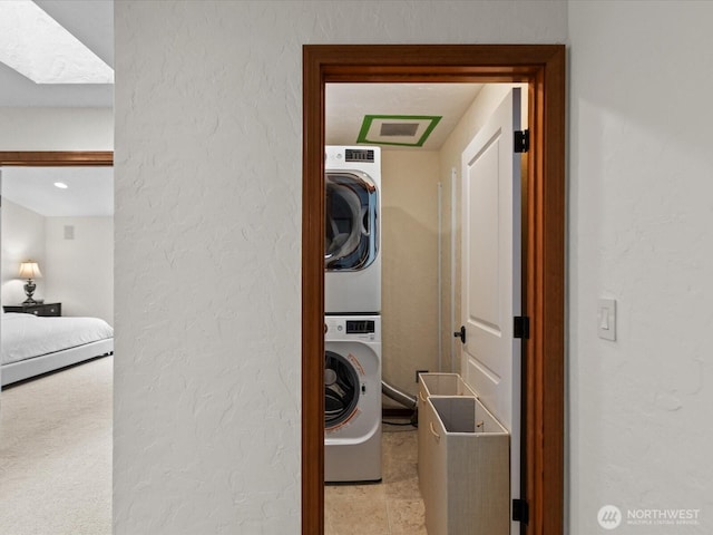 laundry room featuring stacked washer / dryer and a textured wall