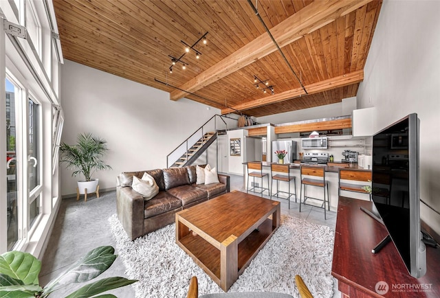 living area featuring wooden ceiling, rail lighting, stairway, and baseboards