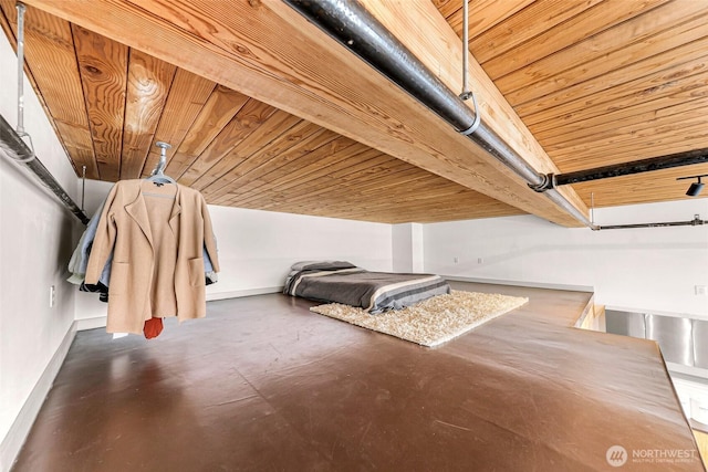 unfurnished bedroom featuring wood ceiling, finished concrete flooring, and baseboards