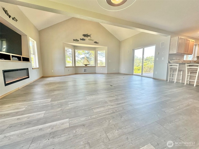 12 Diamond Dr, Pacific Beach, WA 98571 - unfurnished living room with light wood finished floors, a glass covered fireplace, and high vaulted ceiling