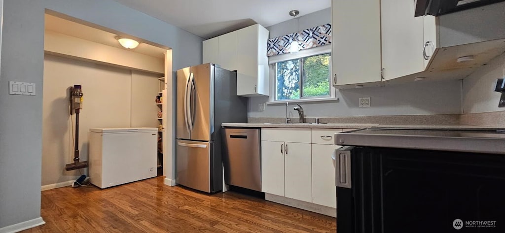 kitchen with stainless steel appliances, a sink, light wood finished floors, and white cabinets