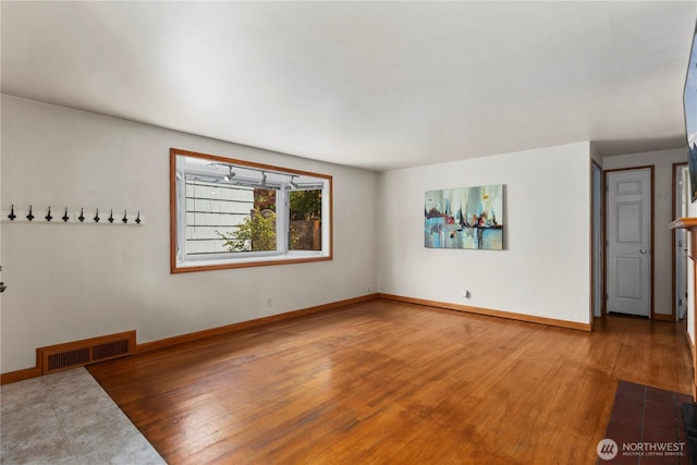 unfurnished living room featuring wood finished floors and baseboards