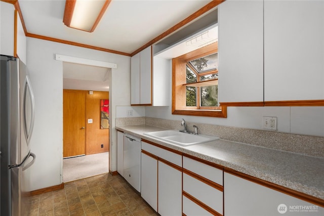 kitchen with freestanding refrigerator, a sink, dishwasher, white cabinets, and stone finish floors