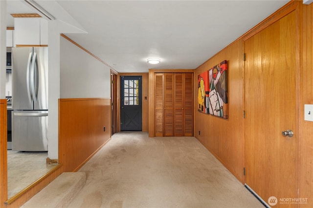 entrance foyer with wooden walls, light carpet, and a wainscoted wall