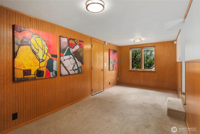 carpeted empty room featuring wood walls