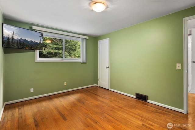 spare room featuring hardwood / wood-style flooring and baseboards