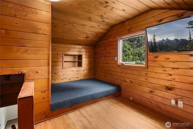 unfurnished bedroom featuring lofted ceiling, light wood finished floors, wooden walls, and wooden ceiling