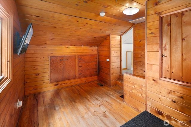 additional living space featuring lofted ceiling, light wood-type flooring, wood walls, and wood ceiling