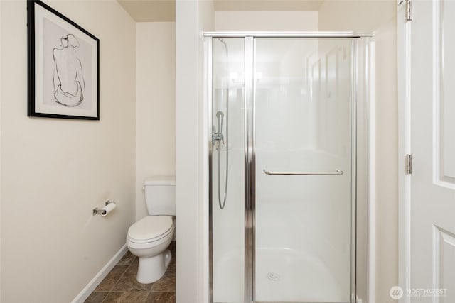 bathroom with baseboards, a shower stall, and toilet