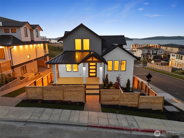 view of front of home with board and batten siding, a fenced front yard, a standing seam roof, and metal roof