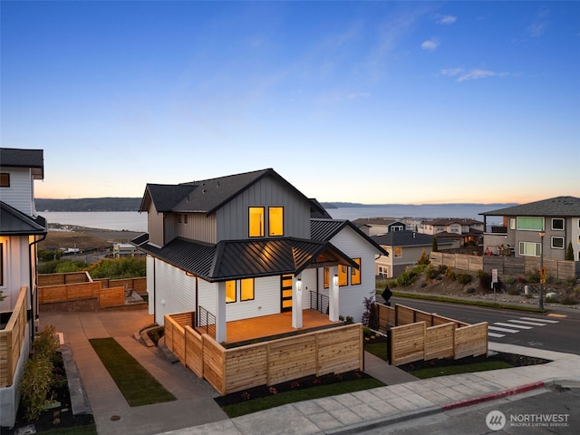 view of front of property featuring board and batten siding, a standing seam roof, metal roof, covered porch, and a water view