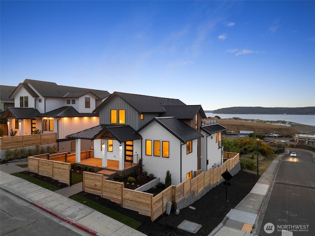 modern inspired farmhouse featuring a standing seam roof, board and batten siding, metal roof, and a water view