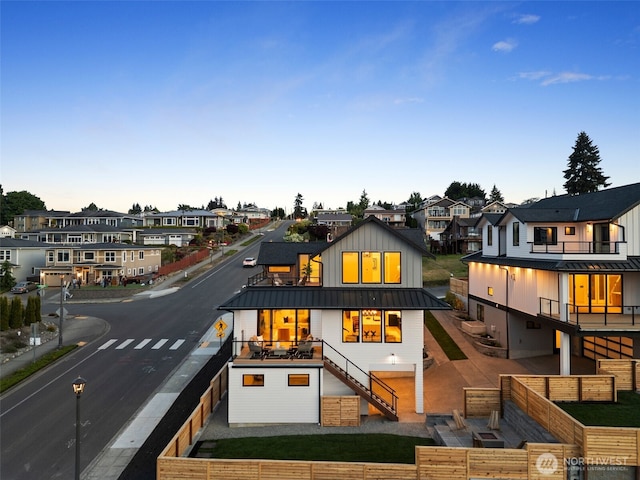 rear view of property with a residential view, a standing seam roof, board and batten siding, stairway, and metal roof