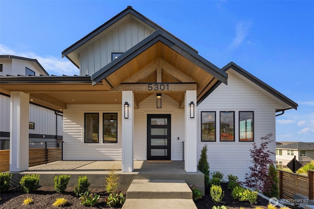 view of front of house featuring board and batten siding, covered porch, and fence