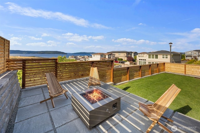 view of patio / terrace with a fire pit, a water view, and a residential view