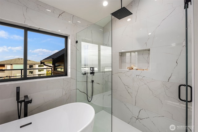 full bathroom with a marble finish shower, a soaking tub, and tile walls