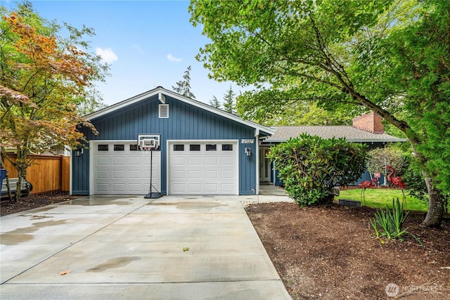 view of front of house featuring concrete driveway, a garage, fence, and a chimney
